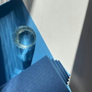 A blue yoga mat with a glass reflecting sunlight, creating a calm and relaxed ambiance.
