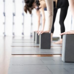 A group of women practicing yoga using blocks in a bright studio setting.