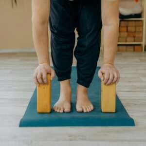 A person practicing yoga using blocks on a mat indoors, focusing on balance.